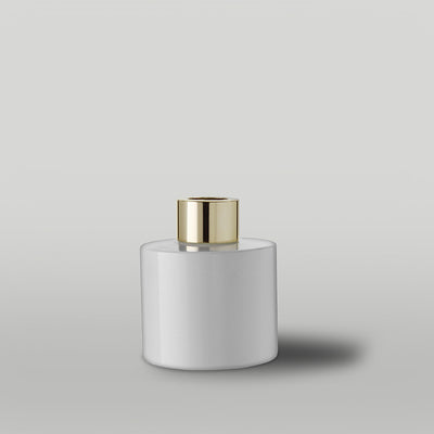 Gloss white diffuser bottle with a gold cap on a light grey background