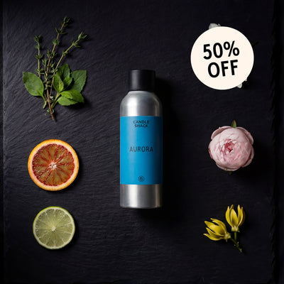 Aurora fragrance oil on a dark surface with fruits and flowers, featuring a 50% off badge.