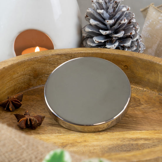 Silver lid for candle jars on a wooden tray