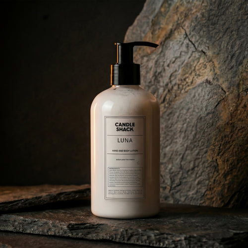 Lotion bottle labeled 'Candle Shack Luna' on a stone surface with a dark background