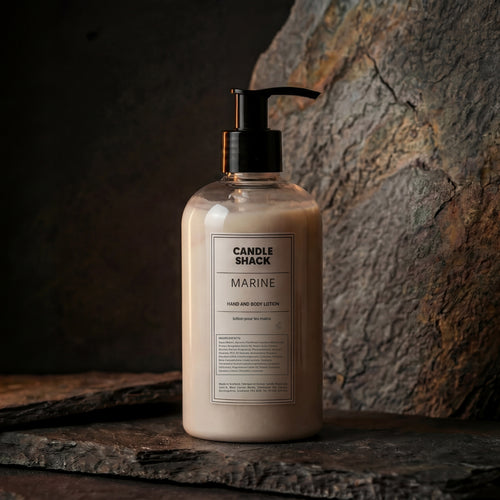 Bottle of Sahara hand and body lotion from Candle Shack on a stone surface with a stone wall background.