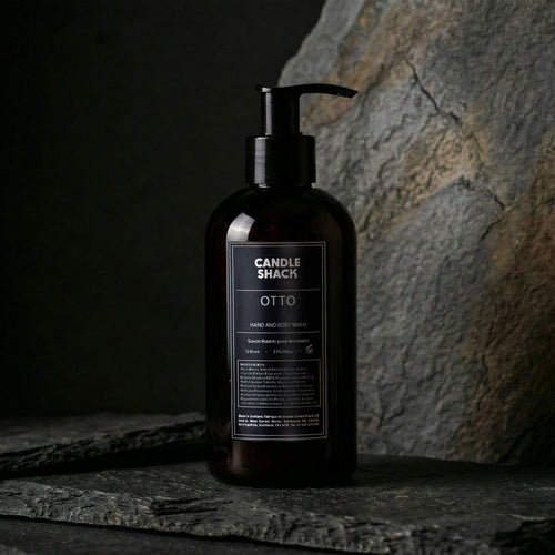 Black bottle Hand and body wash with pump labeled 'Candle Shack Otto' on a dark stone surface.
