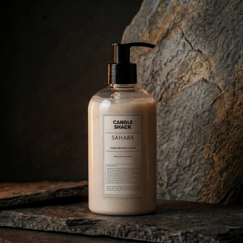 Bottle of Sahara hand and body lotion from Candle Shack on a stone surface with a stone wall background.