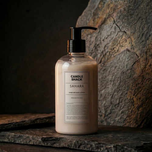 Bottle of Sahara hand and body lotion from Candle Shack on a stone surface with a stone wall background.