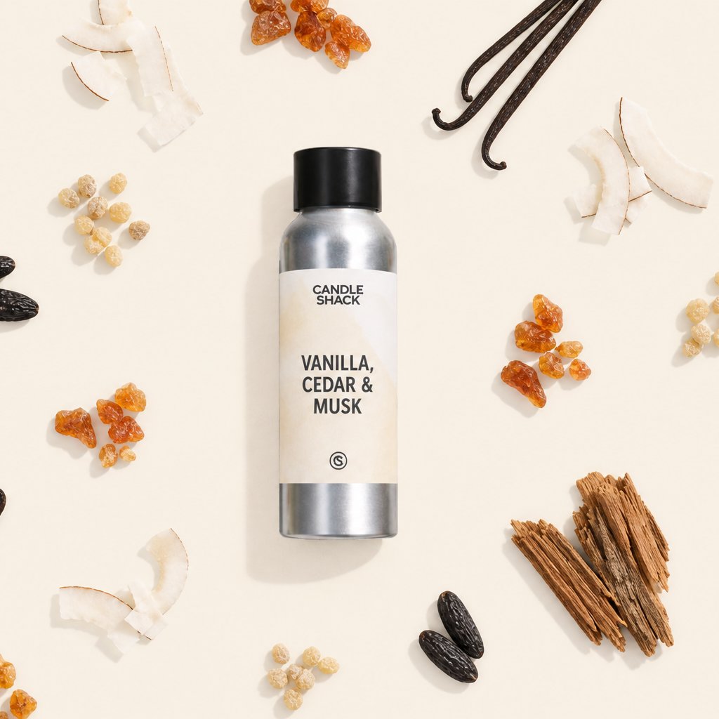 A silver bottle of Candle Spark Vanilla, Cedar & Musk fragrance centered on a cream background, surrounded by flat-lay ingredients including vanilla beans, cinnamon sticks, coconut shells, and dried citrus peels.