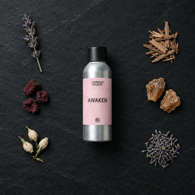 Awaken fragrance oil - Candle Shack aluminium bottle with dried botanicals on a dark slate background