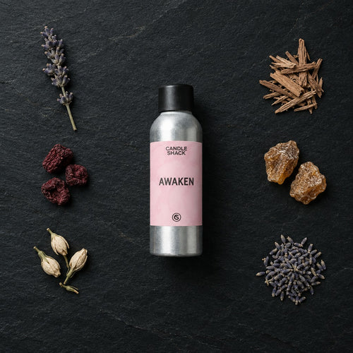 Awaken fragrance oil - Candle Shack aluminium bottle with dried botanicals on a dark slate background