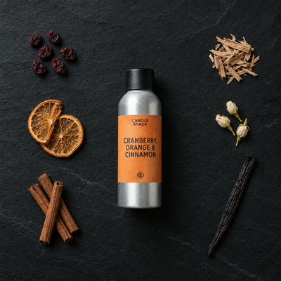 Cranberry, Orange and Cinnamon fragrance oil - Candle Shack aluminium bottle with dried botanicals on a dark slate background