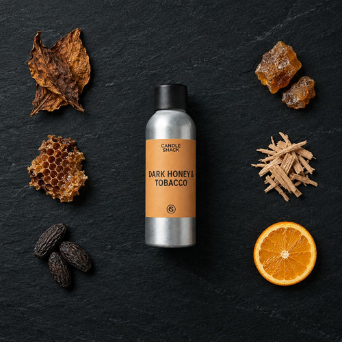 Dark Honey & Tobacco fragrance oil - Candle Shack aluminium bottle with dried botanicals on a dark slate background
