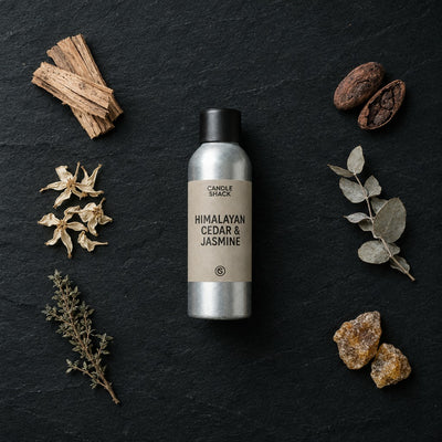 Himalayan Cedar & Jasmine fragrance oil - Candle Shack aluminium bottle with dried botanicals on a dark slate background
