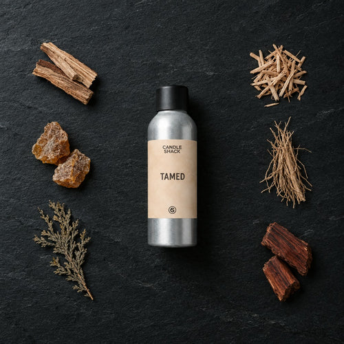 Tamed fragrance oil - Candle Shack aluminium bottle with dried botanicals on a dark slate background