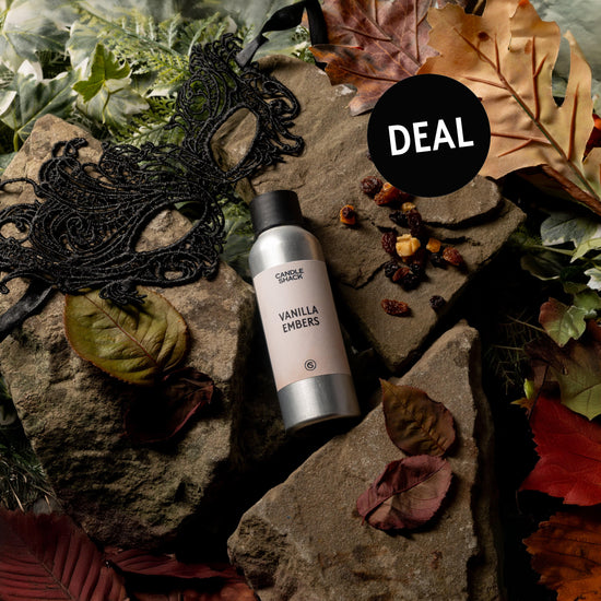 Vanilla Embers fragrance bottle on rocks with scattered leaves and a mask